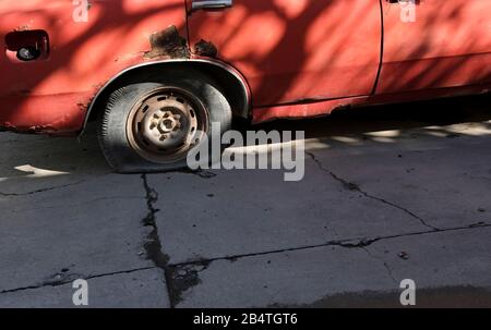 Zerbrochenes Auto mit Rostschäden und einem flachen Reifen Stockfoto