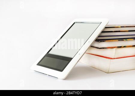 E-Book-Leser in pinkfarbenem Fall auf einem Haufen alter Bücher Stockfoto