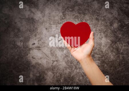 Weltgesundheitstag, Frauen halten rotes Herz auf grunge schwarzen Hintergrund Stockfoto