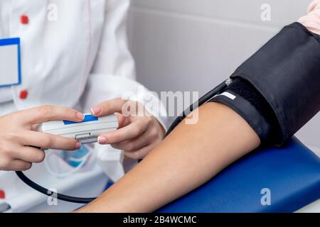 Der Arzt kontrolliert den Blutdruck der jungen Frau in der Nähe. Stockfoto