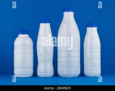 Kunststoff-Milchflaschen isoliert auf blauem Hintergrund Stockfoto