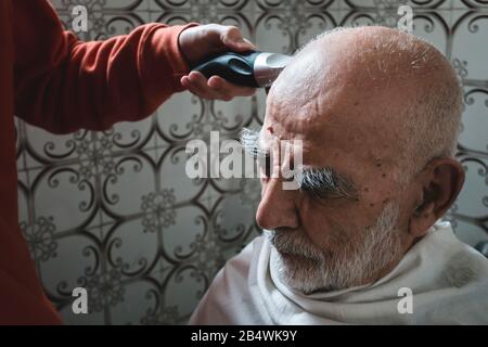 Sehr Alt, Weißhaarig, balger Mann Bekommt Haarschnitt Im Alten Vintage-Bad (Retro exotischer Look) Stockfoto