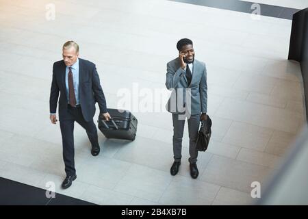 Horizontaler Hochwinkelschuss von zwei modernen Geschäftsleuten, die Zeit im Flughafen verbringen, Kopierraum Stockfoto
