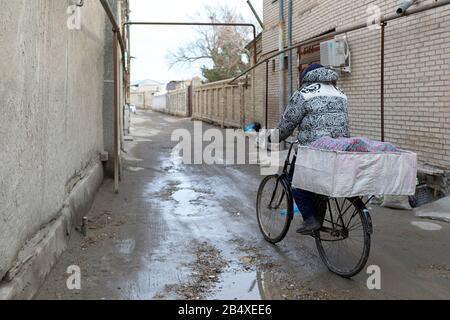 Brotverkäufer, der typisches Brot auf dem Fahrrad aus der Bäckerei in der Altstadt von Buchara, Usbekistan, mitführt Stockfoto