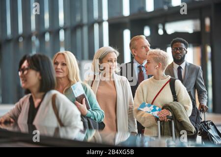 Zwei Frauen plaudern, während sie in der Zollwarteschlange des Flughafens stehen, horizontales mittleres Porträt, Kopierbereich Stockfoto
