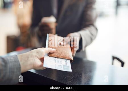 Unerkennbarer Mann, der seinen Pass und sein Flugticket an einen nicht erkennbaren Mitarbeiter des Check-in, einen horizontalen Nahschuss, einen Kopierraum gibt Stockfoto
