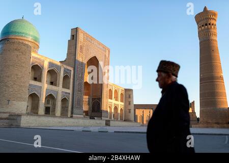 Älterer Einheimischer mit Pelzhut auf der Straße vor dem Kalyan Minarett und dem Po-i-Kalyan Moschee Komplex, Buchara, Usbekistan Stockfoto