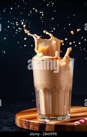 Iced Coffee with Splash in Tall Glass on Dark Background. Konzept Erfrischendes Sommergetränk. Stockfoto