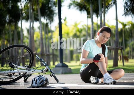 Radverletzungen. Junge Radfahrerin ist beim Radsport vom Straßenrad gefallen. Fahrradunfall, verletztes Knie. Stockfoto