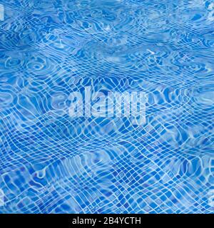 Das Licht, das auf der Oberseite der Wasseroberfläche des Pools reflektiert wurde, war unten mit blauen Mosaikfliesen ausgekleidet. Das Wasser wellt sich auf der Rückseite des blau gefliesten Schwimmbads Stockfoto