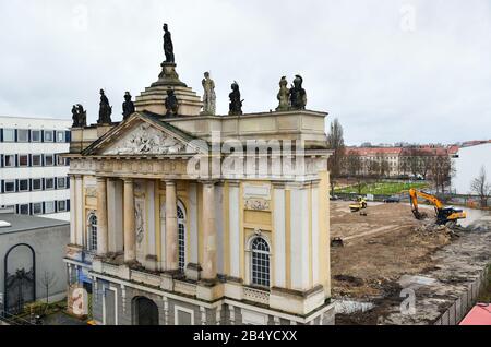 03. März 2020, Brandenburg, Potsdam: Hinter dem Portal der Garnisonkirche erstreckt sich ein abgeflachter sandiger Bereich. Links befindet sich das Gebäude des ehemaligen Rechenzentrums (DVZ) des Bezirks Potsdam und heute das Kunst- und Kreativhausrechenzentrum der Stiftung Sozialpädagogisches Institut Berlin (SPI). Die Kirche wurde in den Jahren von 1730 bis 1735 nach den Plänen des Architekten Philipp Gerlach erbaut und galt als ein Hauptwerk des preussischen Barock. Nach der Bombardierung durch die Alliierten am 14. April 1945 blieben nur noch Ruinen übrig, die erst 1968 gesprengt und abgetragen wurden. Das Recon Stockfoto