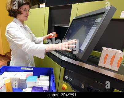 Leipzig, Deutschland. März 2020. Ein Apotheker in der Rosapotheke im Auwald füllt mit einem Computer das Arzneigeschäft, in dem ein Roboter arbeitet. Auf Wunsch eines Computers holt der Roboter die benötigten Medikamente und andere Medikamente aus den meterhohen Fächern und transportiert sie über ein Transportsystem zum Dispens im Verkaufsraum. Kredit: Waltraud Grubitzsch / dpa / Alamy Live News Stockfoto