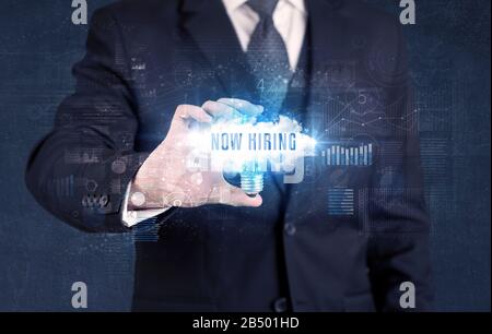 Geschäftsmann, der eine Glühbirne mit JETZT EINSTELLENDER Aufschrift hält, neues Geschäftskonzept Stockfoto