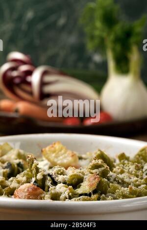 Glutenfreie Kasserolle (Pasta al Forno) mit Gemüse und Käse auf einem Holztisch. Stockfoto