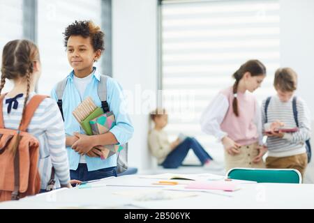 Horizontaler Schuss von fünf jungen Mittelschülern, die während der Schulpause hängen, Kopierraum Stockfoto