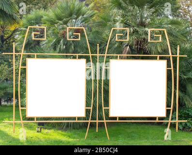 Leeres Plakat mit Straßenwerbung im Park auf dem Hintergrund tropischer Pflanzen. Informationsbanner, Kopierraum Stockfoto
