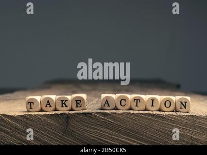 Die Worte Handeln auf kleinen Holzblöcken auf einem Holztisch mit Platz für Text oder Bild Stockfoto