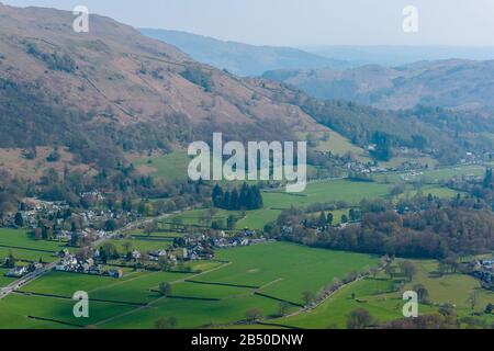 Grasmere Dorf, Fairfield Hufeisen und Loughrigg fielen in den Hintergrund, vom Gipfel von Helm Crag, Grasmere, Lake District, Cumbria, Großbritannien gesehen Stockfoto