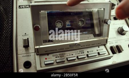 Der alte Kassettenspieler fügt eine Kassette in die Boombox ein. Retro-Kassettenspieler-Konzept. Stockfoto