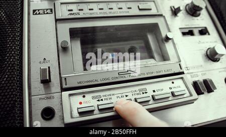 Der alte Kassettenspieler fügt eine Kassette in die Boombox ein und drückt die Wiedergabetaste. Retro-Kassettenspieler-Konzept. Stockfoto