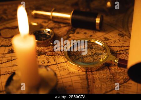 Sammlung antiker Objekte auf der alten Weltkarte im Kerzenlicht Stockfoto