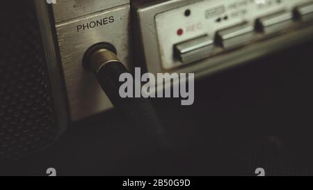 Der alte Kopfhöreranschluss des Kassettenspielers wird an eine Kopfhörerbuchse angeschlossen. Retro-Musik-Konzept. Stockfoto