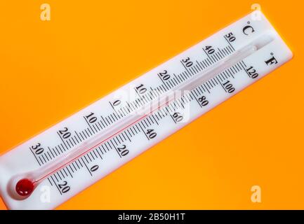 Das weiße Thermometer mit Skala auf orangefarbenem Hintergrund. Startplatz für Design Stockfoto