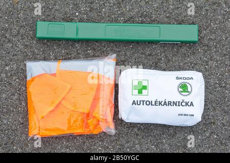 Erste Hilfe, orangefarbene Weste und grünes Straßenschild im Auto von Skoda Auto auf einer Asphaltstraße. Notfall-Werkzeugsatz für die erste Hilfe nach dem Auto Stockfoto