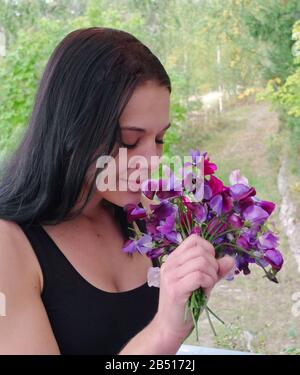 Frau mit duftendem süßen Erbsenstrauß Stockfoto