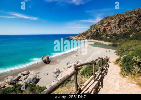 Fantastischer Preveli-Strand mit türkisfarbenem Wasser und felsigen Hügeln. Menschen schwimmen in azurblauem Wasser und sonnen sich auf Sand. Touristen, die sich auf der sonnigen Insel Crete entspannen Stockfoto