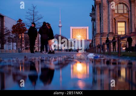 Berlin, Deutschland. März 2020. Passanten stehen am Abend neben dem Reichstags-Gebäude (r) vor dem Berliner Fernsehturm. Credit: Christoph Soeder / dpa / Alamy Live News Stockfoto