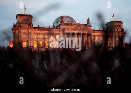 Berlin, Deutschland. März 2020. Das Reichstaggebäude scheint angesichts der Abendsonne hinter einer Hecke. Credit: Christoph Soeder / dpa / Alamy Live News Stockfoto