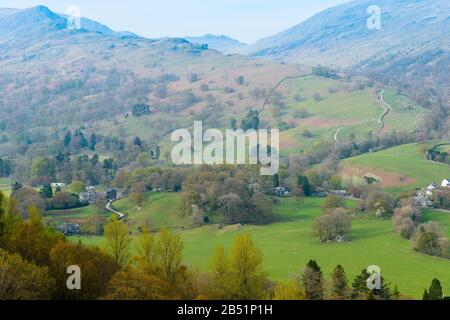 Hazy Fells und Woodland in der Nähe der Stadt Ambleside aus Loughrigg Fell, Lake District, Cumbria, England, mit Blick nach Nordosten an einem Aprilabend. Stockfoto