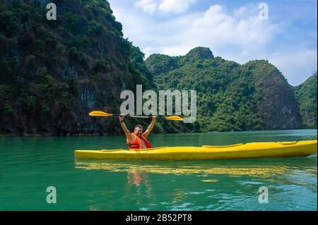 Glücklicher bärtiger Mann mit Ruderkajak in der ha Long Bay. Halong Bay ist eine beliebte Touristenattraktion in Vietnam für Freizeit- und Sportaktivitäten. Stockfoto