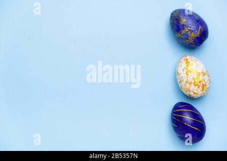 Frohe Ostern. Rahmen für Text aus ostereiern trendig blau, weiß und Golden auf blau gefärbt. Minimaler Stil, Draufsicht, Ebenbild, Kopierbereich. Stockfoto