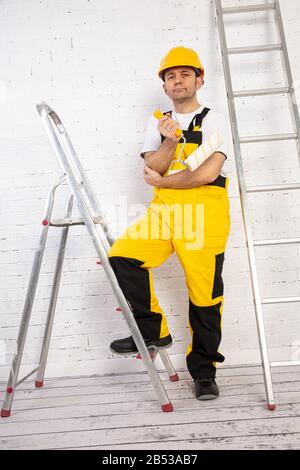 Ein professioneller Maler kompakt und jederzeit einsatzbereit. Er trägt typische Schutzkleidung, die auf der Baustelle verwendet wird. Stockfoto