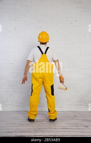 Ein professioneller Maler kompakt und jederzeit einsatzbereit. Er trägt typische Schutzkleidung, die auf der Baustelle verwendet wird. Stockfoto