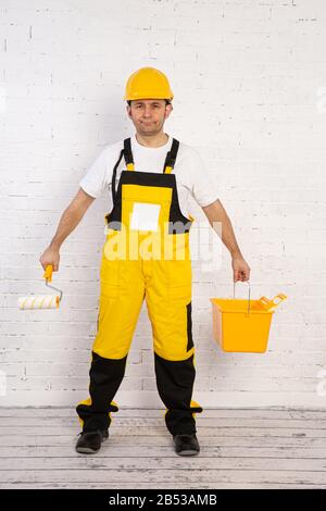 Ein professioneller Maler kompakt und jederzeit einsatzbereit. Er trägt typische Schutzkleidung, die auf der Baustelle verwendet wird. Stockfoto