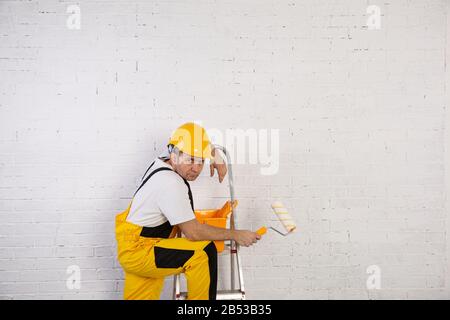 Ein professioneller Maler kompakt und jederzeit einsatzbereit. Er trägt typische Schutzkleidung, die auf der Baustelle verwendet wird. Stockfoto