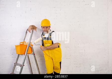Ein professioneller Maler kompakt und jederzeit einsatzbereit. Er trägt typische Schutzkleidung, die auf der Baustelle verwendet wird. Stockfoto