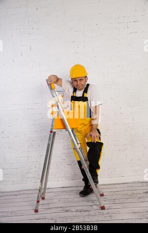 Ein professioneller Maler kompakt und jederzeit einsatzbereit. Er trägt typische Schutzkleidung, die auf der Baustelle verwendet wird. Stockfoto