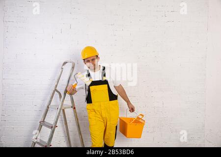 Ein professioneller Maler kompakt und jederzeit einsatzbereit. Er trägt typische Schutzkleidung, die auf der Baustelle verwendet wird. Stockfoto