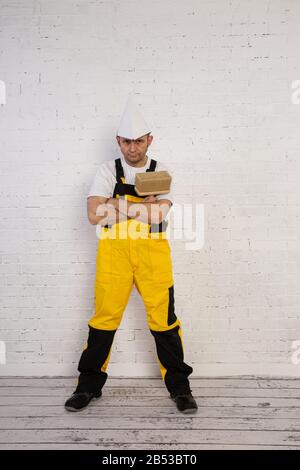Ein professioneller Maler kompakt und jederzeit einsatzbereit. Er trägt typische Schutzkleidung, die auf der Baustelle verwendet wird. Stockfoto