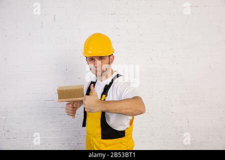 Ein professioneller Maler kompakt und jederzeit einsatzbereit. Er trägt typische Schutzkleidung, die auf der Baustelle verwendet wird. Stockfoto