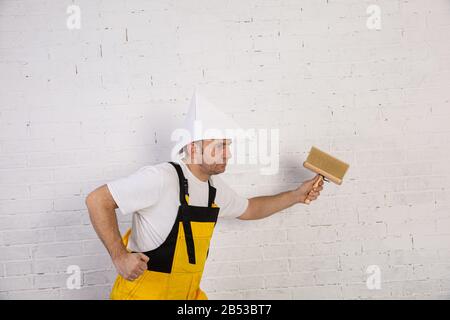 Ein professioneller Maler kompakt und jederzeit einsatzbereit. Er trägt typische Schutzkleidung, die auf der Baustelle verwendet wird. Stockfoto