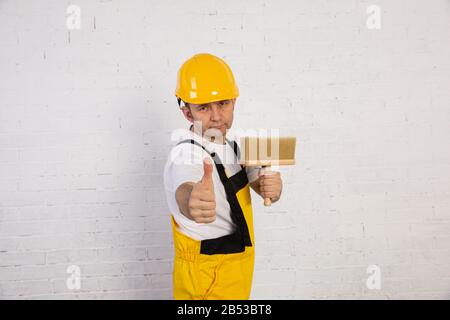 Ein professioneller Maler kompakt und jederzeit einsatzbereit. Er trägt typische Schutzkleidung, die auf der Baustelle verwendet wird. Stockfoto