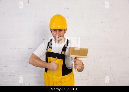 Ein professioneller Maler kompakt und jederzeit einsatzbereit. Er trägt typische Schutzkleidung, die auf der Baustelle verwendet wird. Stockfoto