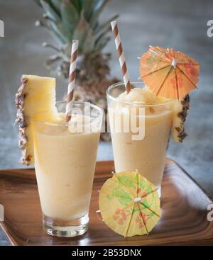 Hausgemachter, gefrorener Rum-Cocktail mit Ananasgarnierung, Strohhalmen und Papierschirmen Stockfoto