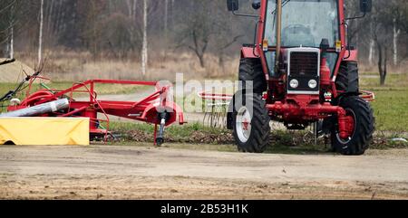 Kleine Landwirtschaft mit Traktor und Pflug im Feld. Stockfoto