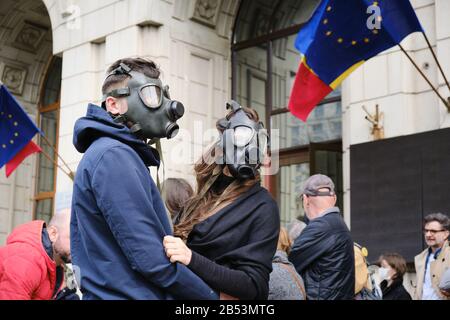 Bukarest, Rumänien - 4. März 2020: Paar trägt aus Protest gegen extreme Luftverschmutzung Gasmasken vor dem Gebäude des Umweltministeriums, w Stockfoto